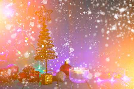 Candle, decor and Christmas tree on the background of Christmas lights. Festive postcard.