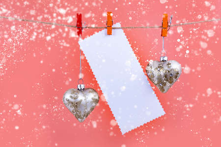 Christmas balls, hearts and a sheet of paper hang on a rope on a blue background. Place for your text. Christmas card.の写真素材