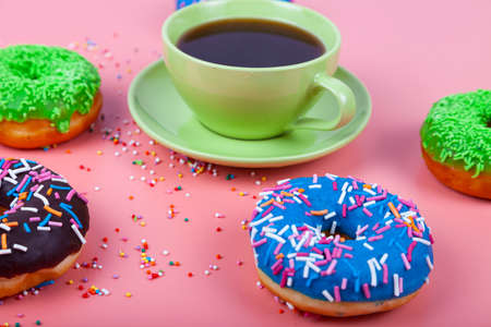 Multicolored donuts and a cup of coffee on a pink background. Delicious still life.の写真素材