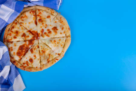 Pizza on a blue background. Delicious pizza cut into pieces close-up.