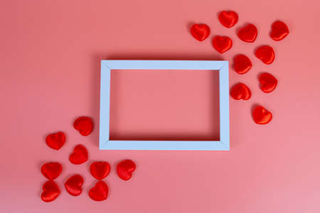 White frame and red hearts on a pink background with place for text.の写真素材