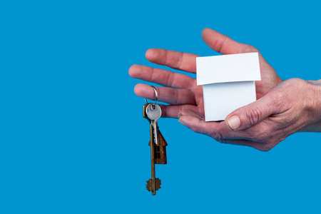 Rent apartments, Real Estate and buying a house idea. blue background. Hand with a toy house and...