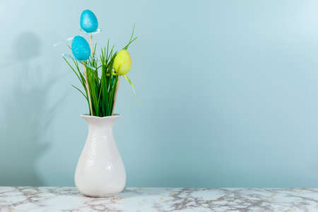 Vase with grass and Easter eggs, space for text, green background. Easter card.の写真素材