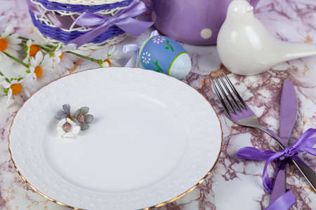 Easter table setting and dinner with flowers, festive decorations, white bird and multicolored eggs. close up.の写真素材