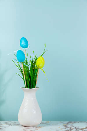 Vase with grass and Easter eggs, space for text, green background. Easter card.の写真素材