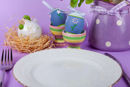Easter table setting and dinner with flowers, festive decorations, white bird and multicolored eggs....