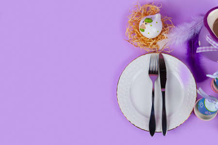 Easter table setting and dinner with flowers, festive decorations, white bird and multicolored eggs, top view, copyspace.の写真素材