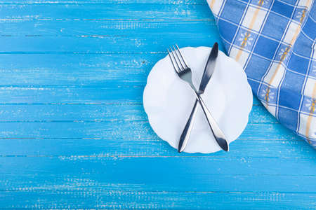 Festive set of cutlery knife and fork with a white dessert plate, blue background, flatley, copyspaceの写真素材