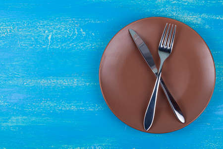Festive set of cutlery knife and fork with a brown plate, blue background, flatley, copyspaceの写真素材