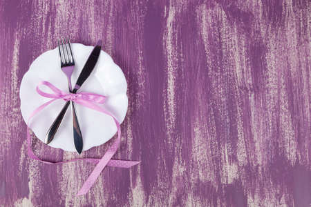 Festive set of cutlery knife and fork with a white dessert plate, purple background, flatley, copyspaceの写真素材