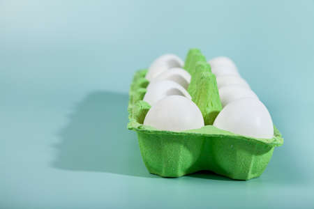 Easter eggs. Chicken white eggs on green background. closeup. selective focus. Green carton crate of fresh eggs. Organic chicken eggs in a egg carton.の写真素材