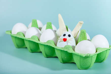 Happy Easter. Easter eggs. Chicken white eggs on green background. One egg with easter bunny ears. closeup.の写真素材