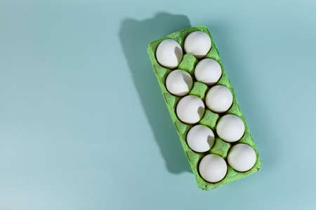Easter eggs. Chicken white eggs on green background. closeup. selective focus. Green carton crate of...