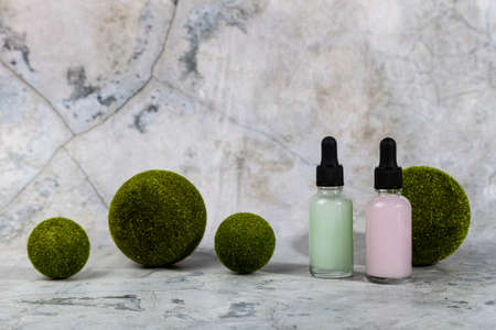 Natural skin care product in glass bottles with Green spheres on a light marble background. Herbal mineral cosmetic. bottles with pipettesの写真素材
