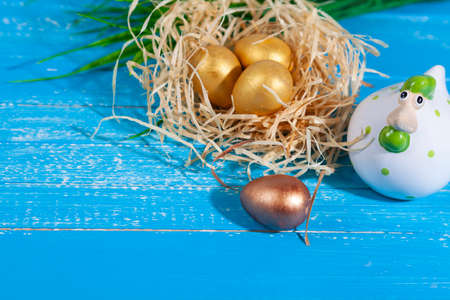 easter greeting card. Easter chick in a nest and golden eggs. Blue wooden background, place for text.の写真素材