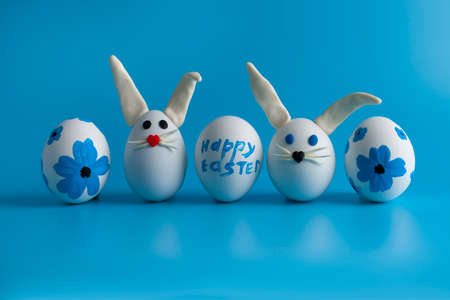Easter composition with Easter eggs decorated with flowers and Easter bunny. Blue background, copy...