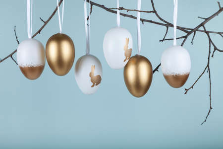 Golden Easter eggs hang on a branch on a green background. copyspace. happy easter greeting card