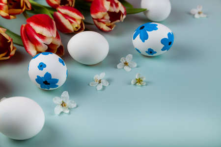 Tulip flowers and easter eggs decorated with flowers on green background. Top view with copy space....