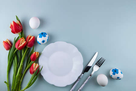 Easter greeting card with colorful yellow eggs, tulips, plate on green background. flat lay....
