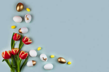 Tulip flowers and golden easter eggs on green background. Top view with copy space. Happy Easter greeting card. border.の写真素材
