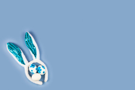 Rabbit ears and Easter eggs on a blue background. easter decor. Flat lay, copy space.の写真素材