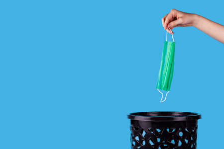 Medical mask are thrown into the trash can. For copy space for designers on a blue background.