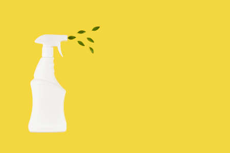 White bottle mockup for cleaning. Eco spray bottle for safe cleaning with green leaves on yellow...
