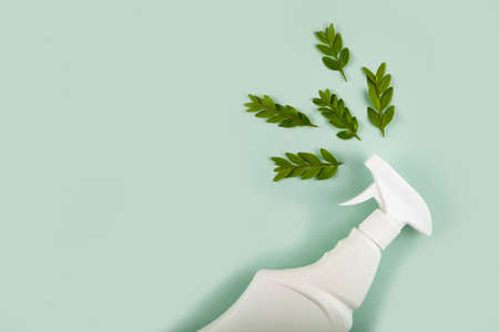 White bottle mockup for cleaning. Eco spray bottle for safe cleaning with green leaves on green background. Copy space, flat lay.の写真素材