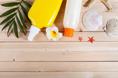 Flat lay composition with sunscreen and seashells on wooden background. Everything for a beach...