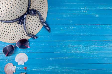 Flat lay composition with hat, sunglasses and seashells on a blue wooden background.の写真素材