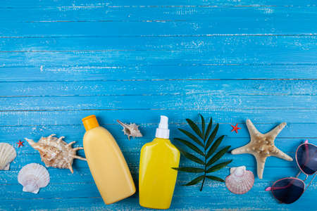 Flat lay composition with sunscreen and seashells on a blue wooden background.の写真素材