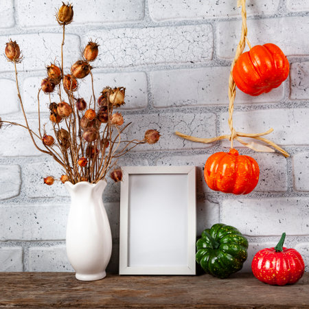 Photo frame mockup with autumn decorations and pumpkins on brick wall background. Thanksgiving, Halloween holiday poster design.の写真素材