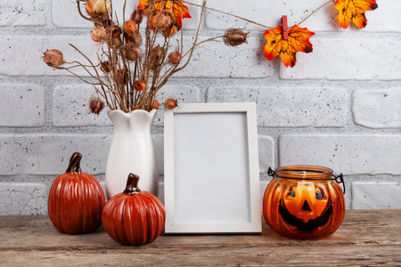 Photo frame mockup with autumn decorations and pumpkins on brick wall background. Thanksgiving, Halloween holiday poster design.の写真素材