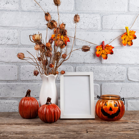 Photo frame mockup with autumn decorations and pumpkins on brick wall background. Thanksgiving, Halloween holiday poster design.の写真素材