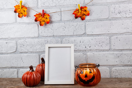 Photo frame mockup with autumn decorations and pumpkins on brick wall background. Thanksgiving, Halloween holiday poster design.の写真素材