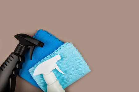 Black and white bottle and cleaning rags. Eco sprayer for safe cleaning on a pastel brown background. Copy space, flat lay.の写真素材