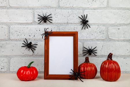 Photo frame mockup with autumn decorations and pumpkins on brick wall background. Thanksgiving, Halloween holiday poster design. Spiders on the wall.の写真素材