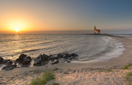 A beautiful beach and lighthouse at sunriseの写真素材
