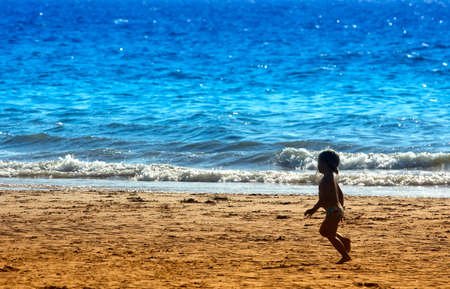 little girl running on the beach in summerの写真素材
