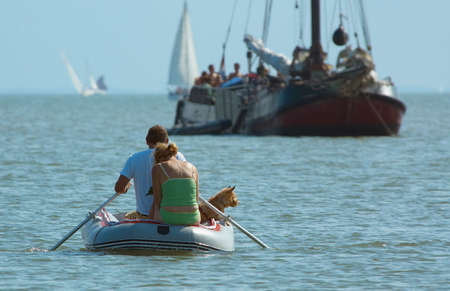 couple with dog rowing towards the shoreの写真素材