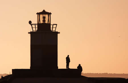 silhouettes of people and a lighthouseの写真素材