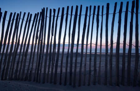 wooden fence on the beach with sunset backgroundの写真素材