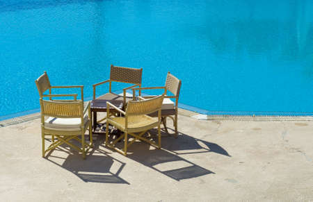 chairs and table on the edge of the swimming poolの写真素材