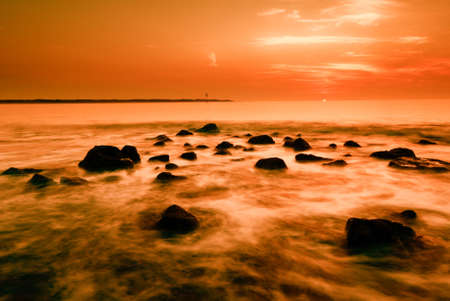abstract sunset image of ocean and rocks taken with a slow shutterspeedの写真素材