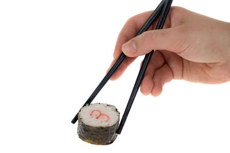 a hand with chopsticks picking up a sushi roll isolated on whiteの写真素材
