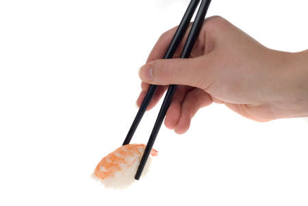 a hand with chopsticks picking up a piece of sushi isolated on whiteの写真素材