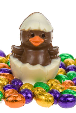 cute easter chick surrounded by chocolate easter eggs isolated on a white background