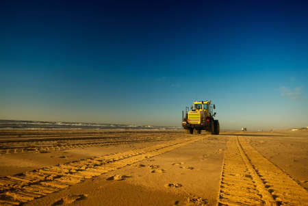 tracks on the beach with a bulldozer in the distanceの写真素材