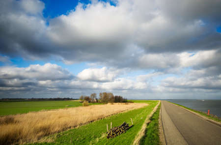beautiful sky on a country road in the netherlands with a lake called the "ijsselmeer" to the leftの写真素材