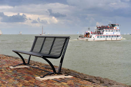 A bench and the boat from volenam to marken in the background, The Netherlandsの写真素材